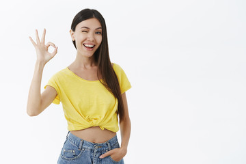 Good-looking female fitness trainer assuring she will help winking joyfully showing okay or...