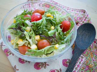 A fresh and healthy salad made with fruits and vegetables in a bowl on a wooden background.