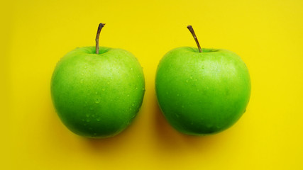 Green apples in water drops - yellow background isolated close up macro top view