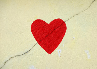 Imprint of a red heart on a crack mason wall.
