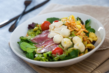 Salad with fusilli pasta accompanied tomatoes, mozzarella, smoked ham and italian cheese