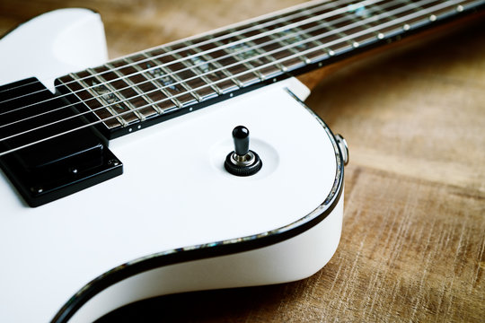 Body and fretboard of modern electric guitar on rustic wooden background. 