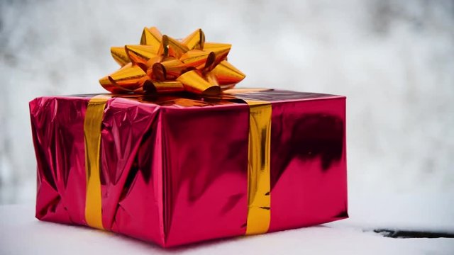 Christmas present gift in red box with gold gliter ribbon outdoor.