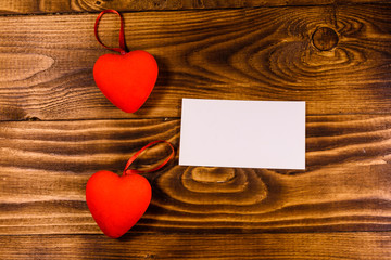Two red hearts on a wooden table. Top view. Blank card