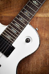 Body and fretboard of modern electric guitar on rustic wooden background. Top view. Copy space. 
