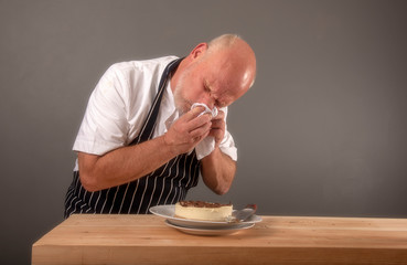 Mature chef sneezing over food ingredients 