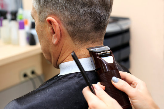 Man having a haircut from hairdresser. Close-up picture of shaving a senior mans head