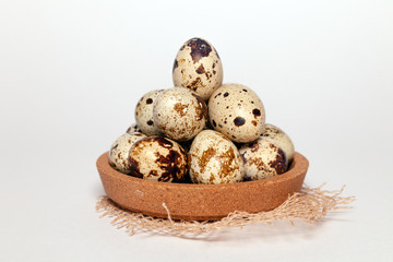 Obraz premium Closeup Easter small fresh textural quail eggs in round wooden bowl with textile isolated on white background. Concept traditional treat Orthodox Christian spring Church holiday. Free space, copyspace