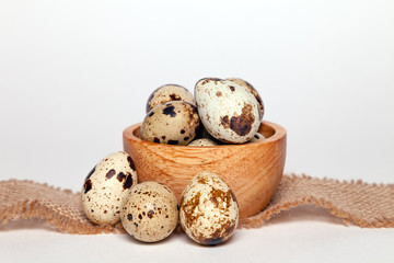 Closeup Easter small fresh textural quail eggs in round wooden bowl with textile isolated on white background. Concept traditional treat Orthodox Christian spring Church holiday. Free space, copyspace