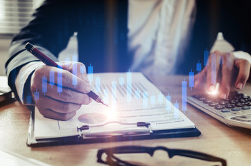 young investor or business man analysis on financial reports and using calculator with graphic...