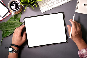 Top view man holding blank screen tablet on  home workspace desk
