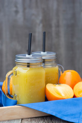 Healthy orange juice with Persimmon, khaki fruits in glass jars, rustic wooden table. Copy space.