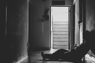 Silhouette of depressed and sad young woman sitting at the front my room, black and white tone, copy space