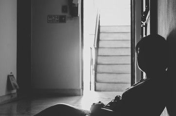 Silhouette of depressed and sad young woman sitting at the front my room, black and white tone, copy space
