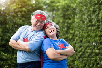 Senior couple in Superhero costume lauging with arms crossed.