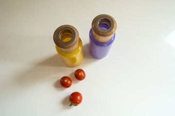 Small red tomatoes and colorful glass bottles with wooden elements