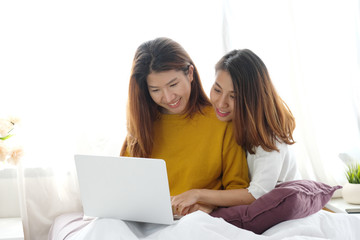 Young cute asia lesbian couple using laptop with happiness at home, lgbt, homosexual, lesbian couple lifestyle