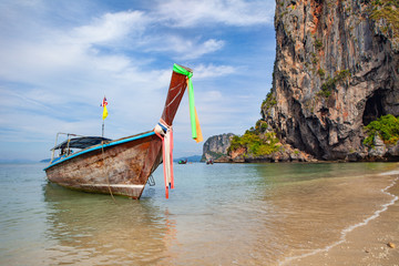 Long tail boat on tropical beach with rock on background
