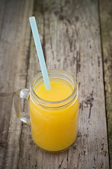 Fresh orange juice in the mason jar on wood table, rustic wooden table. Vertical image.