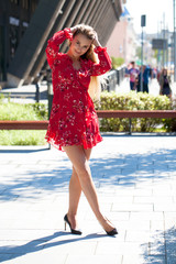 Naklejka premium Sexy blonde model posing on th street in red summer dress