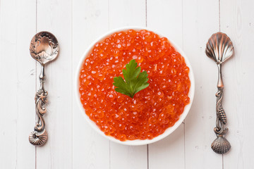 red salmon caviar in a plate on a white table.