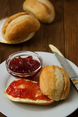 Breakfast with fresh buns and butter, strawbery jam on wooden background. Vertical image.