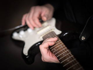 Fototapeta na wymiar Male hands playing on electric guitar, close up, selected focus