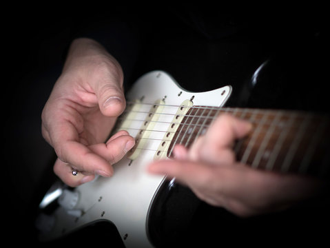 Male hands playing on electric guitar, close up, selected focus