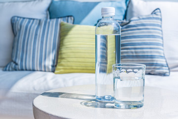 Glass and bottle of drinking water on an outdoor table on sunny day