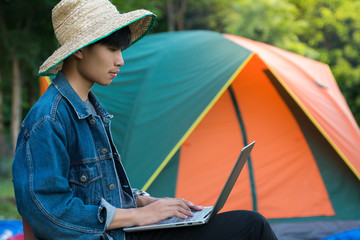 A young man using laptop while camping on his vacation