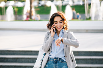 Portrait of nice brunette girl with short hair walking  in city.  She wears shirt, jeans, jacket...