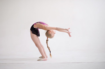 Little girl gymnast, performs various gymnastic and fitness exercises.