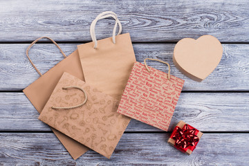Paper shopping bags and gift boxes. Brown paper gift bags and boxes with presents on wooden background. Holiday shopping concept.