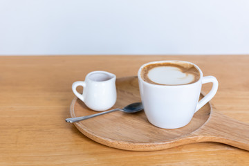 Cappuccino cup coffee with sugar and spoon on wooden plate and wooden table