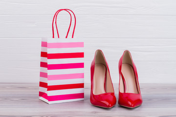Red stilettos and paper gift bag. Luxury female high heels and paper shopping bag, horizontal...