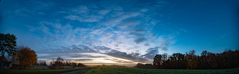 Panorama of sunrise in morning field and forest