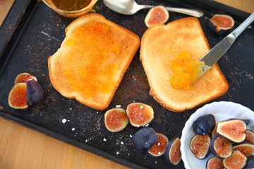 Overhead view of toast, apricot jam and fresh figs on a baking pan