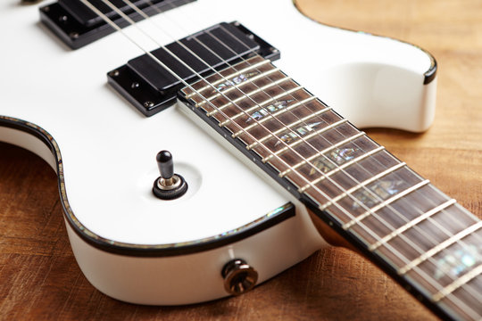 Body and fretboard of modern electric guitar on rustic wooden background. 