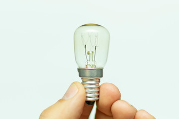 a small light bulb with a tungsten filament in hand, close-up