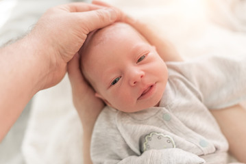 Baby in the hands of mom and dad close up.