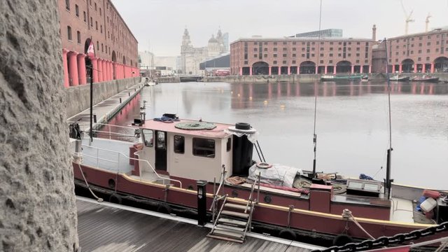 Camera slides to reveal moored barge and warehouses at the Albert Dock, Liverpool