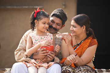 Indian family holding piggy bank at home