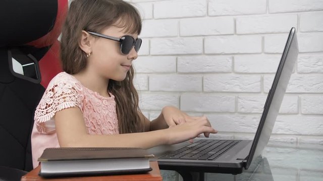 Child wearing pinhole glasses. Little girl in obscura glasses at the laptop.