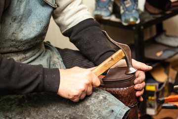 close-up of hands male shoemaker repairing shoes by nailing a heel