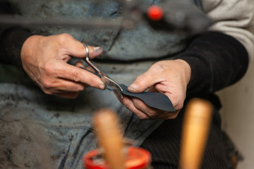 close-up of male shoemaker's hands cutting out shoe soles