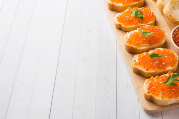 Sandwiches with red salmon caviar on a wooden Board. White table top.