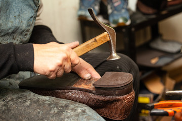 close-up of hands male shoemaker repairing shoes by nailing a heel