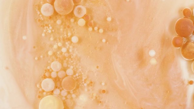 Colorful paint in golden bubbles organically moves in the sand liquid
