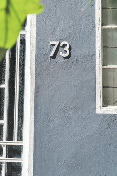 Gray wall of residential building with number of house 73 in neighborhood of Mexico city