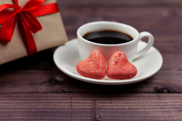 Two hearts, coffee and a gift for Valentine's Day on a wooden background